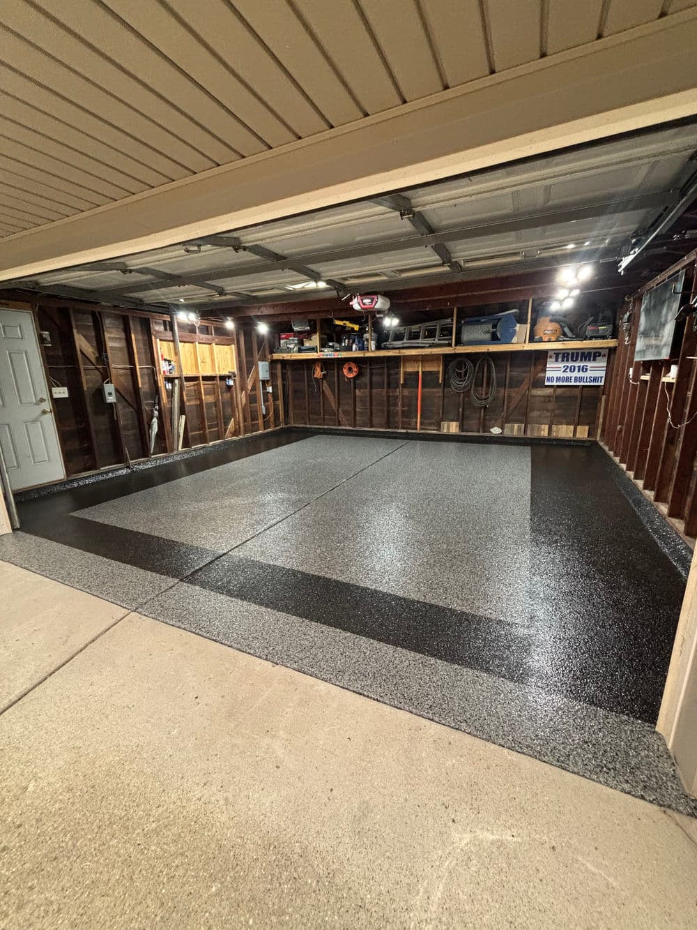 Renovated garage with sleek epoxy floor, organized tools, and well-lit interior.