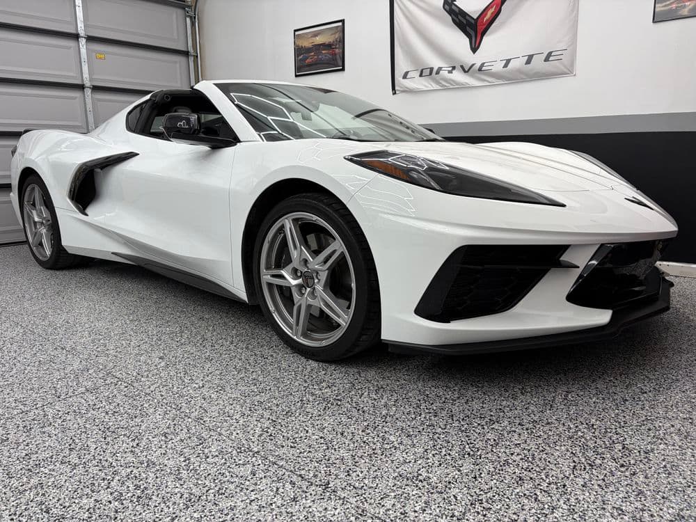 White Corvette C8 parked in a garage, showcasing sleek design and modern features.
